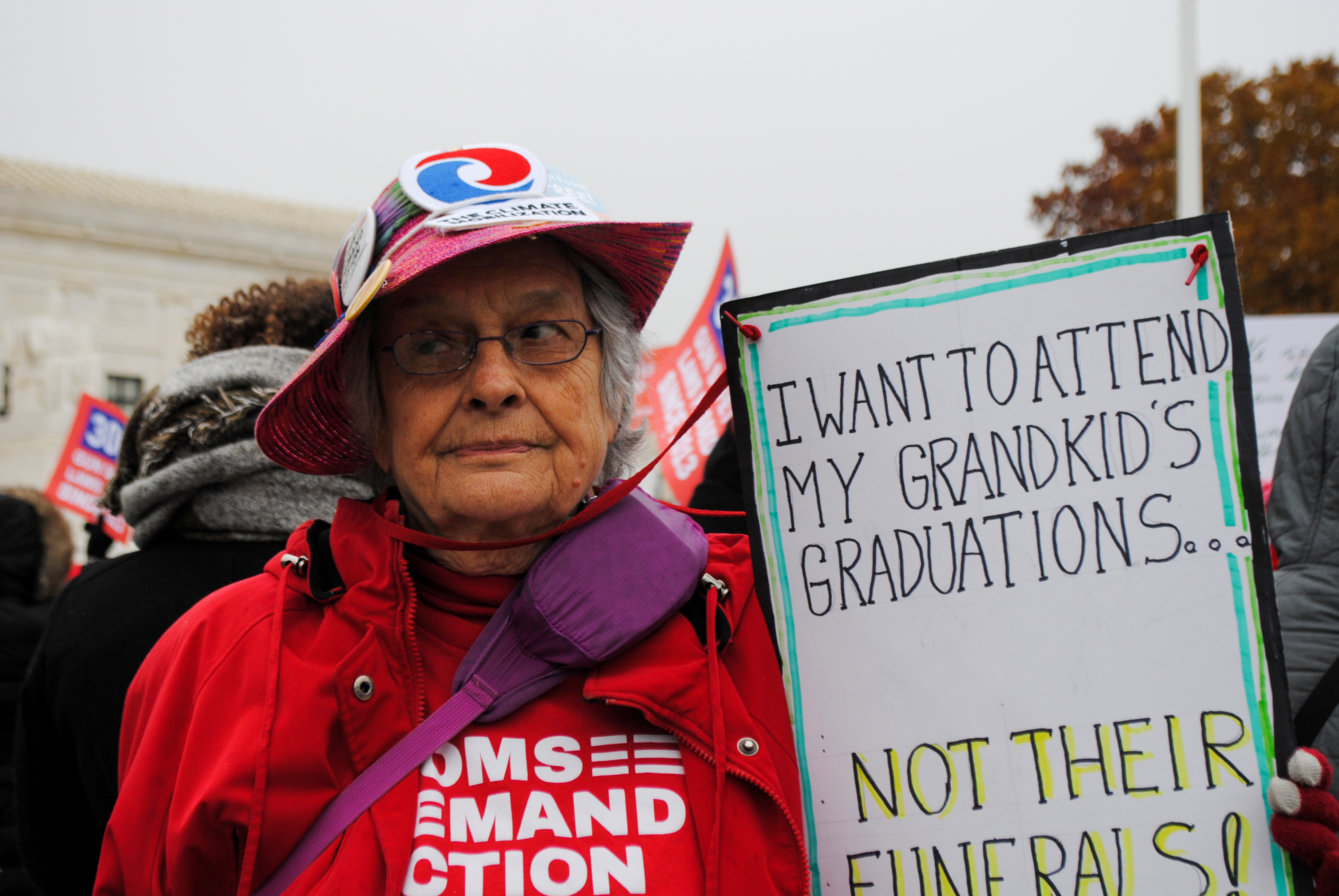 Woman with sign that reads: I want to attend my grandkid's graudations... not their funerals!