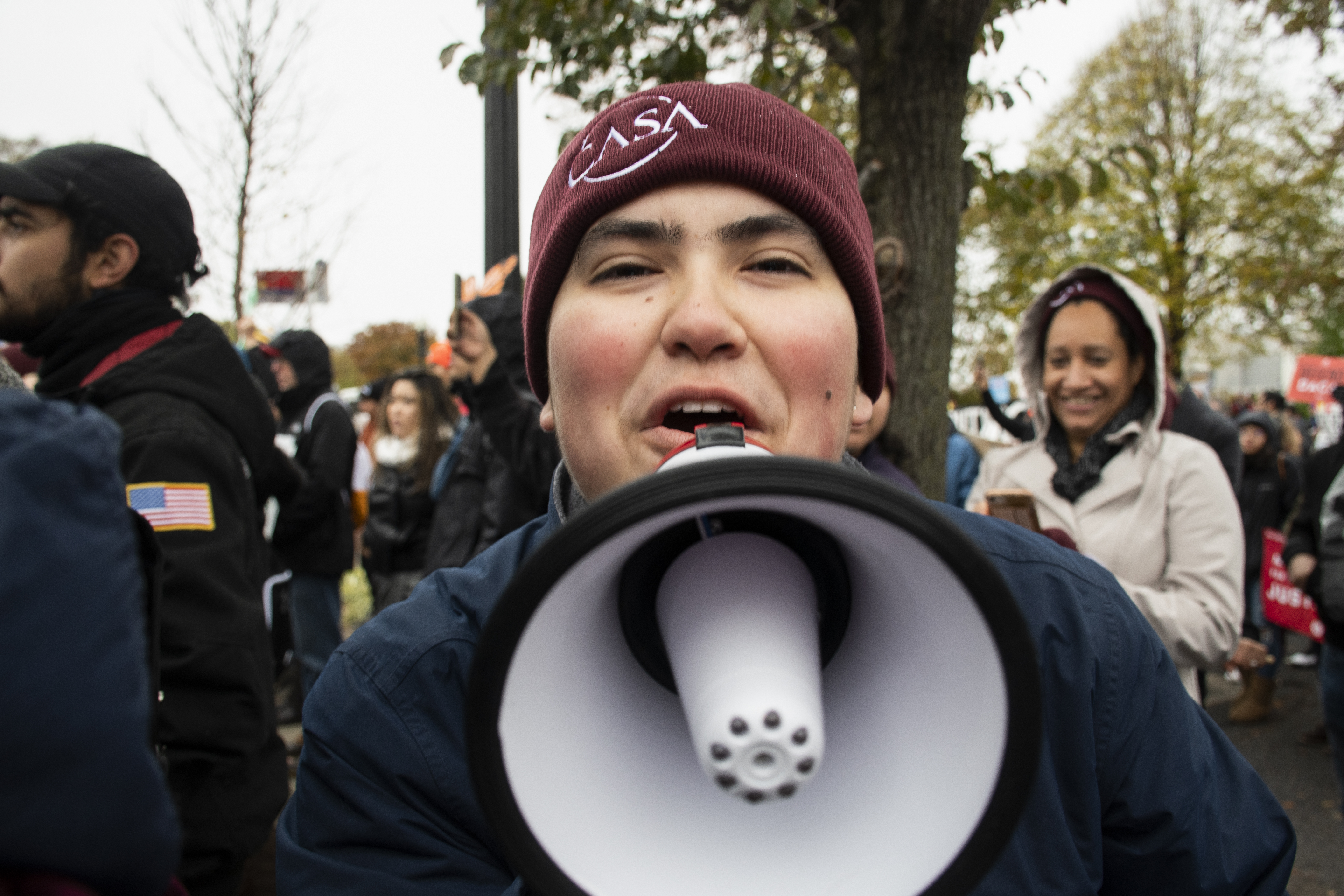 Woman in a CASA hat yells into a megaphone looking directly at the camera